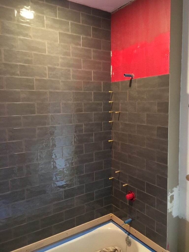 WIP. A mostly-tiled shower with the waterproofing layer exposed.